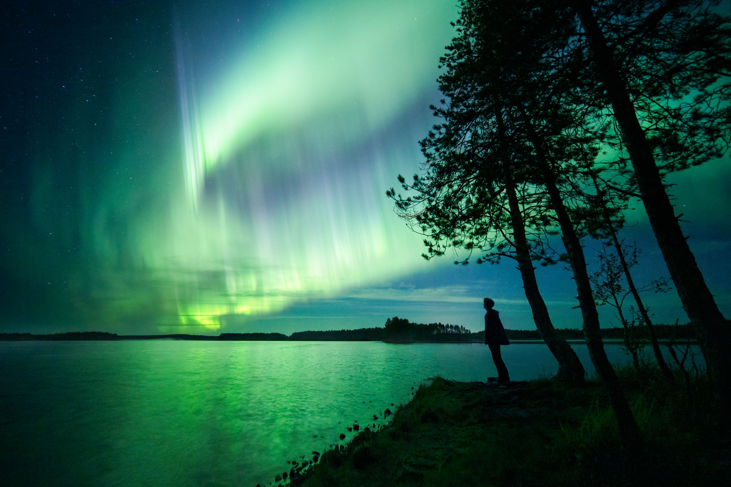 Aurora over a Finnish lake with a lone figure